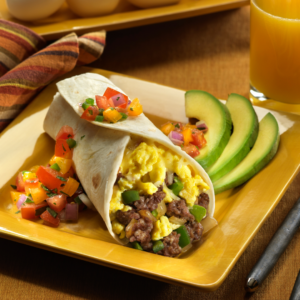 Breaksfast burrito on a plate with salsa and avocados