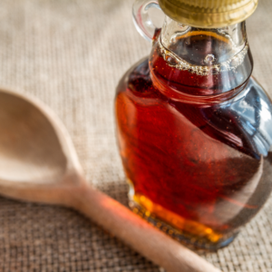 Maple syrup in a jar next to a measuring spoon