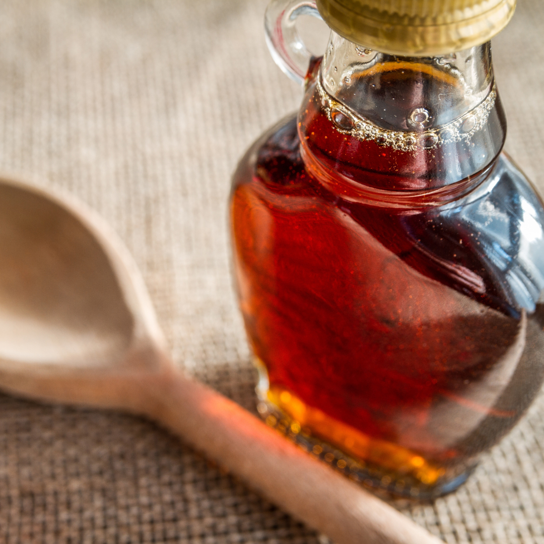 Maple syrup in a jar next to a measuring spoon
