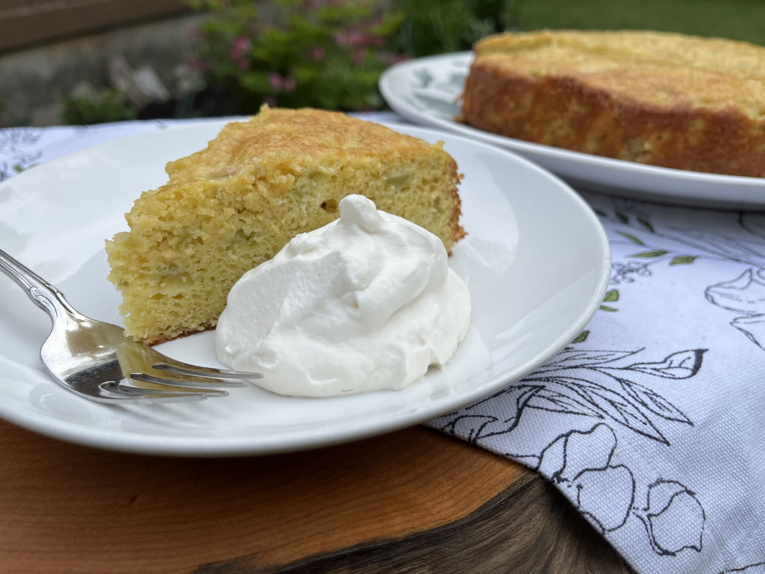 rhubarb yogurt cake on a plate with whipped cream