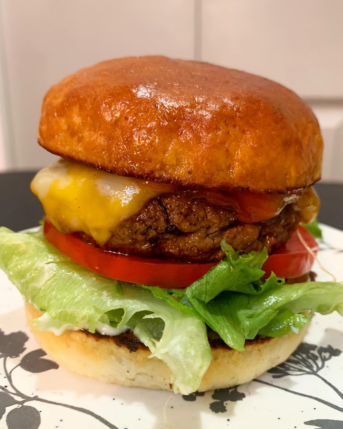 a grilled burger on a bun with cheese, lettuce and tomato