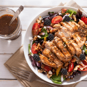 A blackberry chicken salad in a bowl with dressing on the side